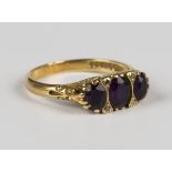 An 18ct gold ring, mounted with three oval cut amethysts and two pairs of rose cut diamond points at