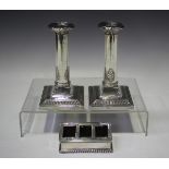 A pair of George V silver candlesticks, each cylindrical stem with anthemion decoration, on a square