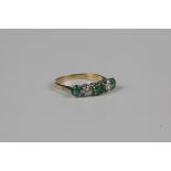 An 18ct gold, platinum, emerald and diamond five stone ring, claw set with three circular cut
