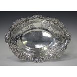 An Edwardian silver oval dish, the outswept scalloped rim decorated in relief with flowers and