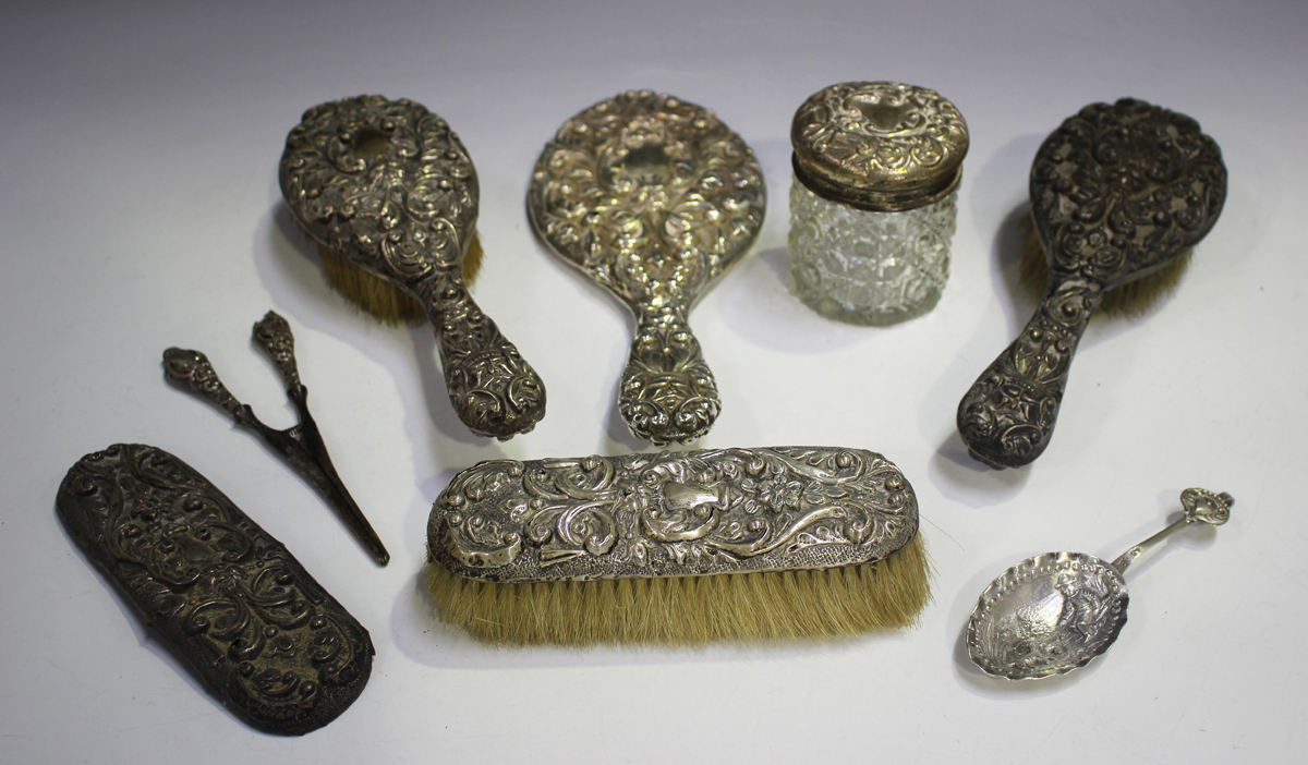 An Edwardian silver mounted six-piece dressing table set, embossed with mask and foliate scrolls,