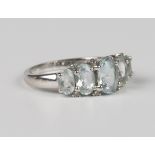 A 9ct white gold, aquamarine and diamond ring, mounted with a row of five graduated oval aquamarines