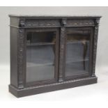 A late Victorian carved oak bookcase, fitted with a pair of a glazed panel doors, on a plinth