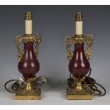 A pair of early 20th century gilt metal and claret lacquered table lamps, height 33cm.Buyer’s