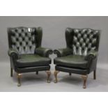 A pair of 20th century George III style wingback armchairs, upholstered in buttoned green leather,
