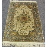 A Kashmir part silk rug, late 20th century, the ivory field with a flowerhead medallion, within a