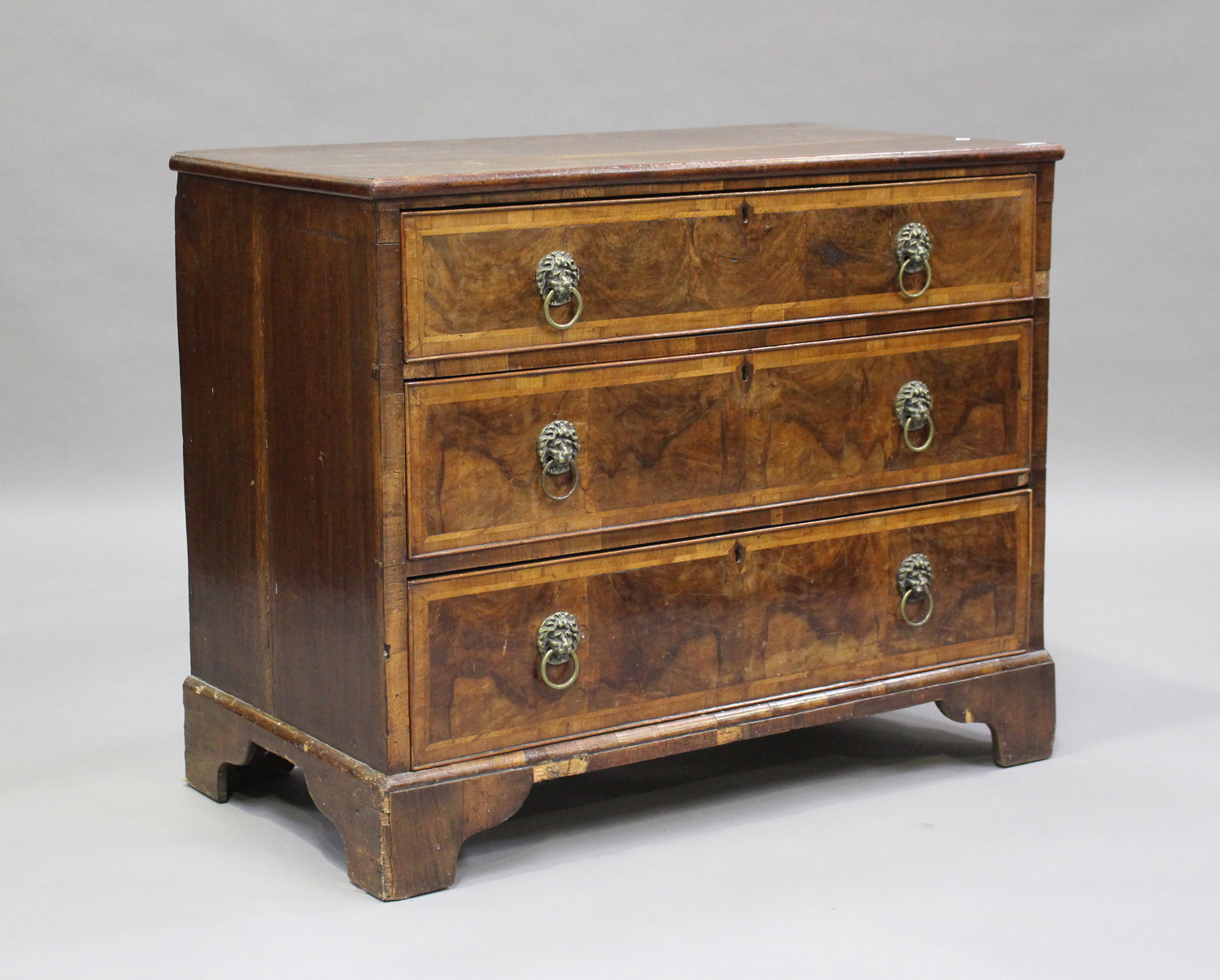 An 18th century oak and walnut chest of three drawers with crossbanded borders, on bracket feet,