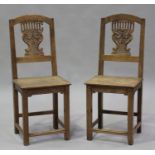 A pair of late 19th century French oak hall chairs with carved and pierced splat backs, the solid