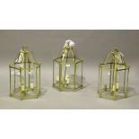 A set of three modern brass framed ceiling lanterns with glazed sides, height 56cm, width 27cm.