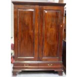 A George V mahogany wardrobe, fitted with a pair of panel doors above two drawers, on bracket