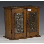 An Edwardian oak smoker's cabinet with inset pressed copper door panels, height 31cm, width 34cm,