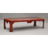 A 20th century red painted chinoiserie coffee table, the glazed top enclosing a foliate painted