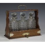 An Edwardian oak and plate mounted three-bottle tantalus, height 32cm, width 36cm (faults).Buyer’s