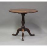 An 18th century oak tip-top circular wine table, on a turned column and tripod cabriole legs, height