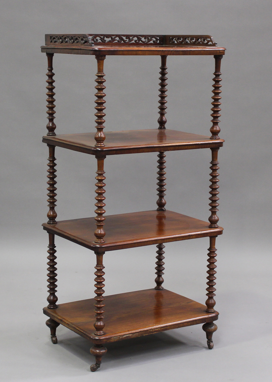 A Victorian mahogany four-tier whatnot with pierced gallery top, raised on bobbin turned supports,