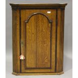 A George III oak hanging corner cabinet, crossbanded in mahogany, the moulded pediment above an
