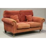 A modern scroll arm two-seat sofa, upholstered in raspberry fabric, on turned legs and castors,