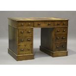 An Edwardian oak twin pedestal desk, the top inset with leather above an arrangement of nine