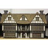 A Robert Stubbs 1/12th scale Tudor Manor doll's house with thatched effect roof, removable roof
