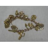 A 9ct gold charm bracelet supporting eighteen 9ct gold and other charms