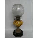 A Victorian brass oil lamp with marbled glass reservoir and etched glass shade on ceramic base