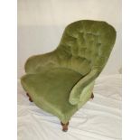 A Victorian mahogany easy chair upholstered in green buttoned fabric on turned legs with casters