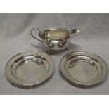 A silver classical-shaped sauce boat with scroll handle on three hoof feet,