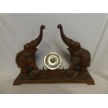 An African carved teak gong stand with twin elephant supports and steel gong