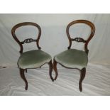 A pair of Victorian rosewood balloon back dining chairs with carved rail backs and upholstered