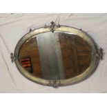 A 1920's bevelled oval wall mirror in beaten pewter frame decorated in relief with flaming torch