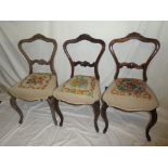 Three matching Victorian carved rosewood dining chairs with rail backs and tapestry seats on scroll