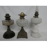 An Edwardian opaque glass oil lamp with brass mounts and two Victorian oil lamps with clear glass
