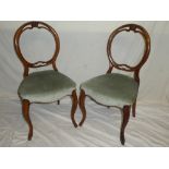 A pair of Victorian walnut balloon back dining chairs with upholstered seats on scroll legs