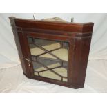 An inlaid mahogany hanging corner cupboard with shelves enclosed by a central astragal glazed door