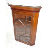 A polished mahogany hanging corner cupboard with shelves enclosed by a single astragal glazed door