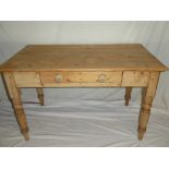 An old polished pine rectangular kitchen table with a single drawer in the frieze on turned tapered
