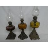 Three various Victorian oil lamps with cast iron bases and tinted glass reservoirs