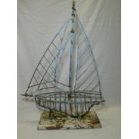 A painted metal and wirework figure of a yacht on painted wood base,