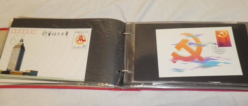 A folder album containing over 70 items of China postal stationary and stamps including first day