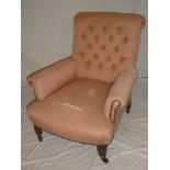 A Victorian mahogany easy chair upholstered in pink buttoned fabric on turned legs with casters