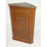 A late Victorian carved oak wall mounted hanging corner cupboard with foliage and classical figure