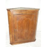 An early 19th Century oak hanging corner cupboard with shelves enclosed by a central panelled door