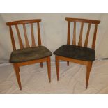 A set of four 1960s teak dining chairs with rail backs and black vinyl seats bearing labels for