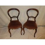 A set of six Victorian rosewood balloon back dining chairs with carved rail backs and upholstered
