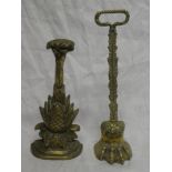 A brass and iron door stop in the form of an animals paw and one other pineapple shaped door stop