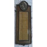 An old bevelled rectangular wall mirror in carved oak frame surmounted by an oval panel containing