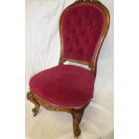 A Victorian walnut occasional chair upholstered in red buttoned fabric on scroll-shaped legs with