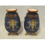 A pair of German Mettlach pottery tapered vases with raised mask head decoration on three scroll