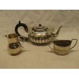 A late Victorian silver oval teapot with gadrooned decoration and ebonised handle,