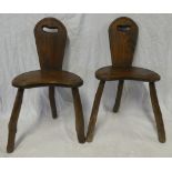 A pair of elm rustic three-legged occasional chairs on natural supports